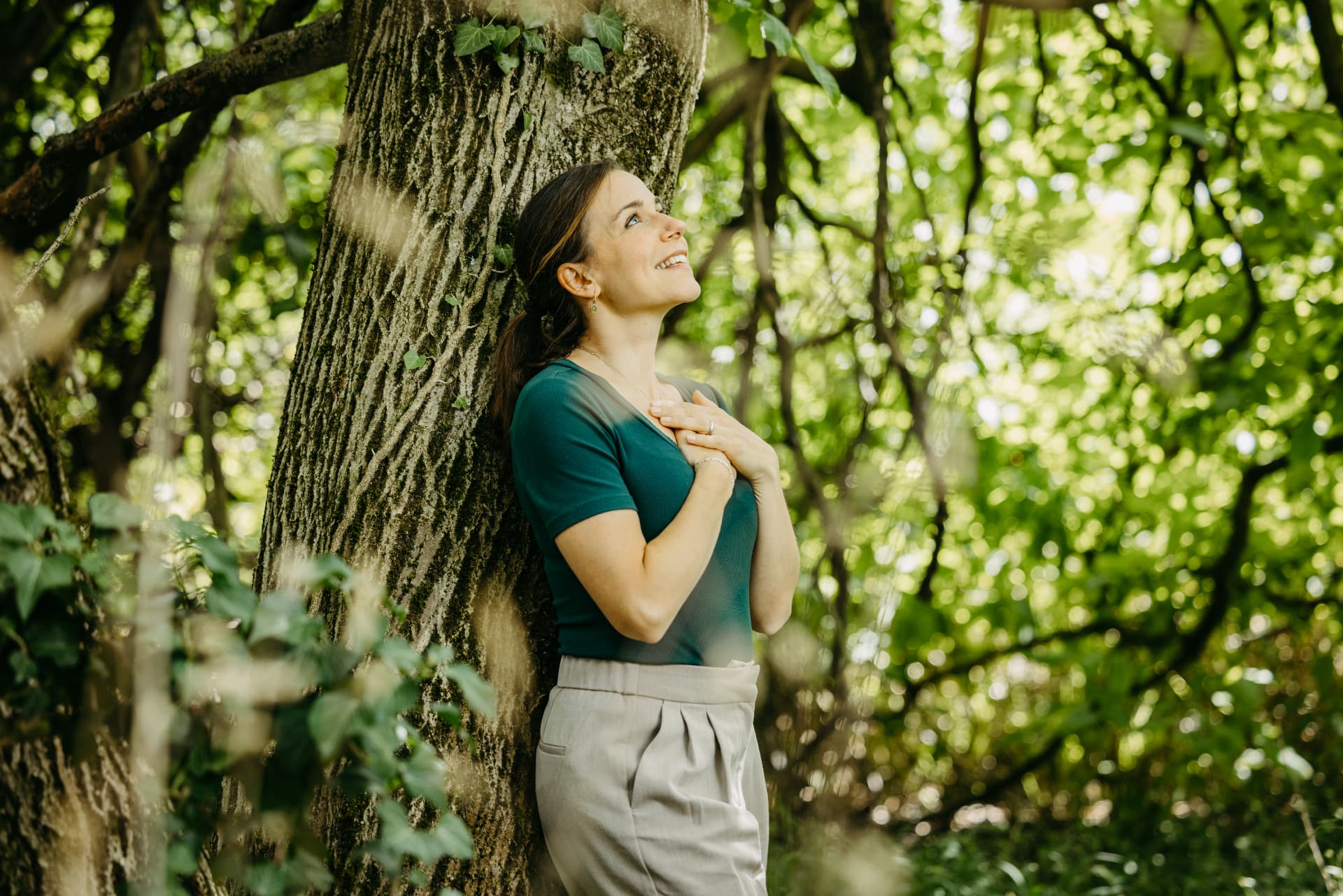 Michèle Winkler lehnt an einem Baum im Wald